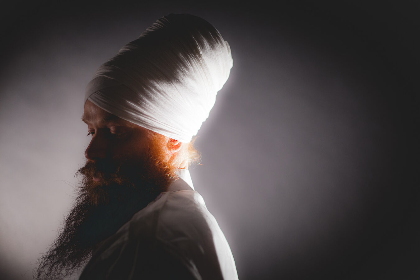 DJ Redlox in profile, white turban lit from behind